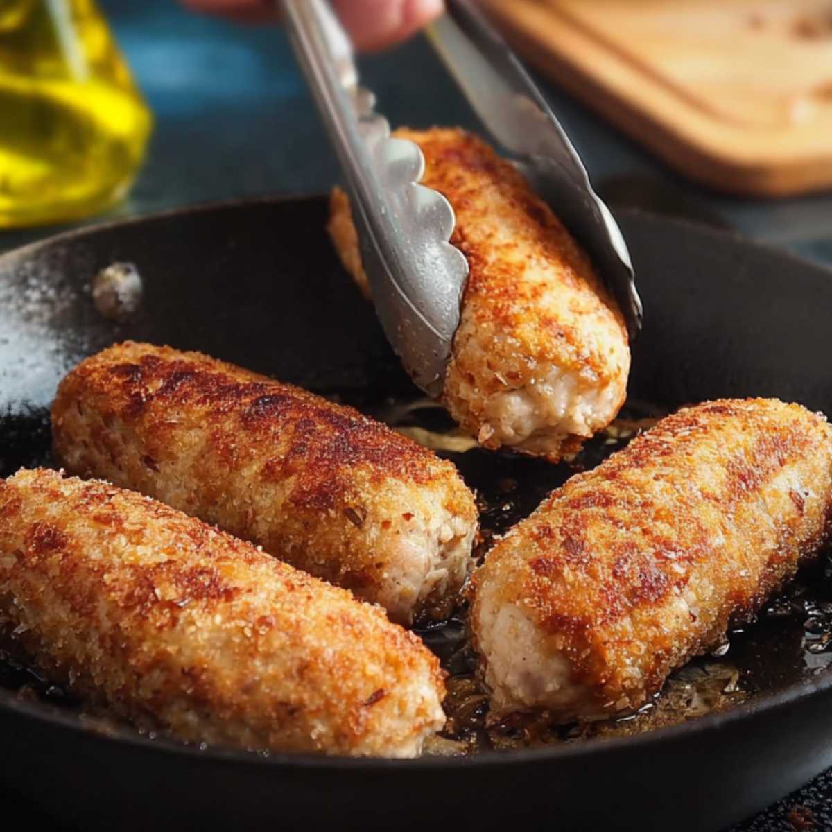  Zrazy z mięsa mielonego panierowane, smażone na złoto w patelni żeliwnej, obracane szczypcami kuchennymi